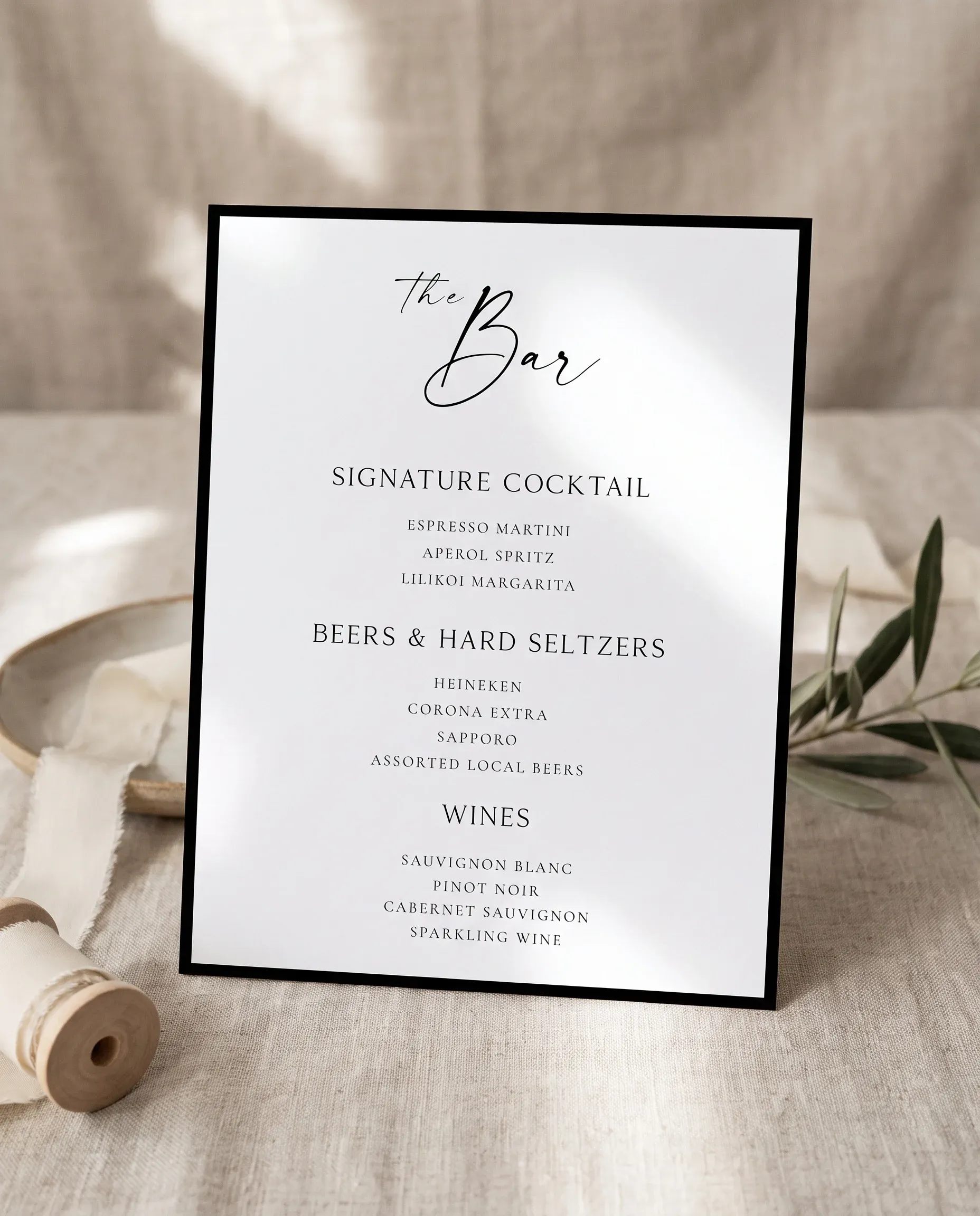 Lumen Frame — bar menu page displayed upright in a styled setting under soft natural light, wedding bar sign.