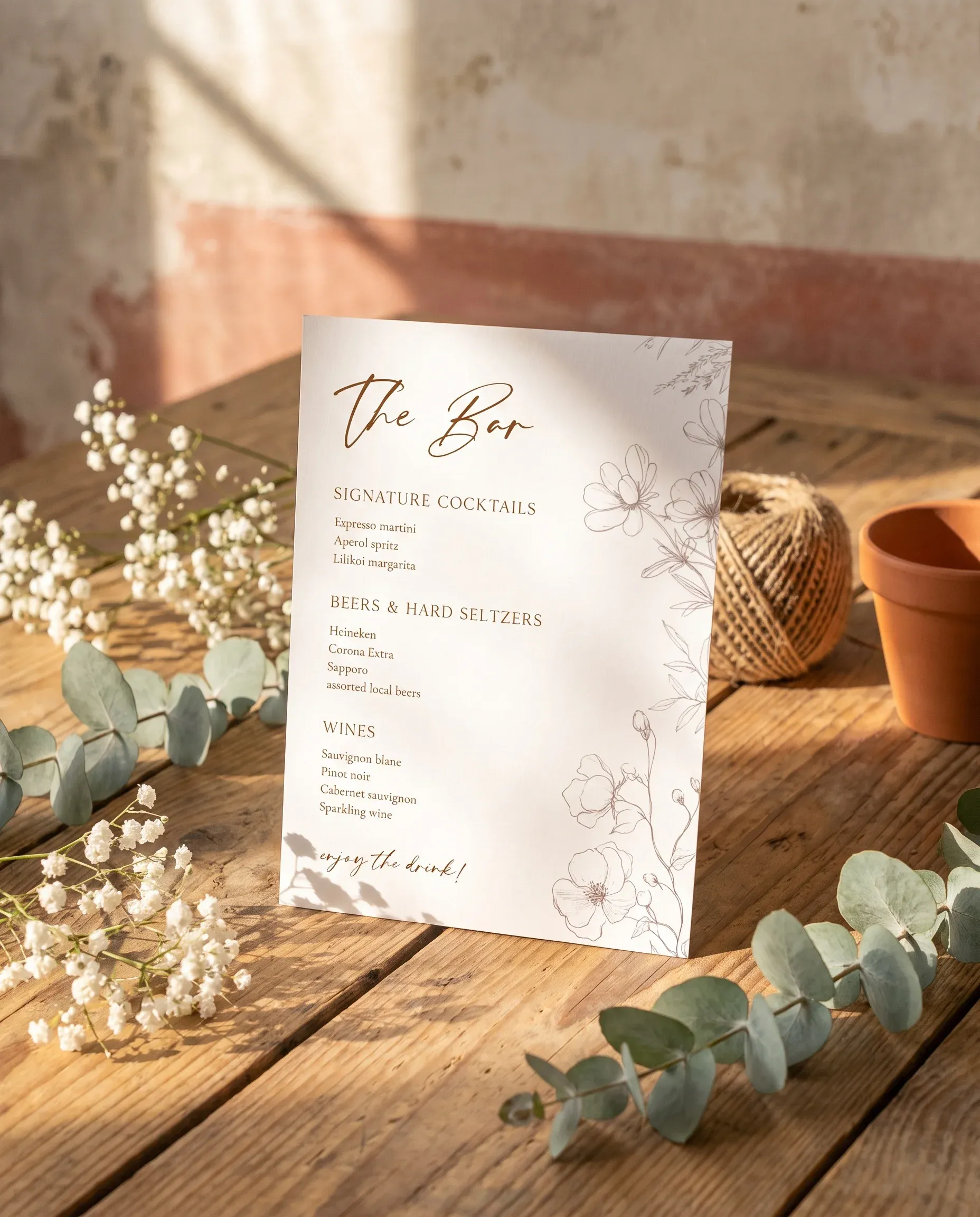 Arrow Bloom — bar menu page displayed upright on premium editorial paper under soft natural light, slight overhead angle, wedding bar sign.