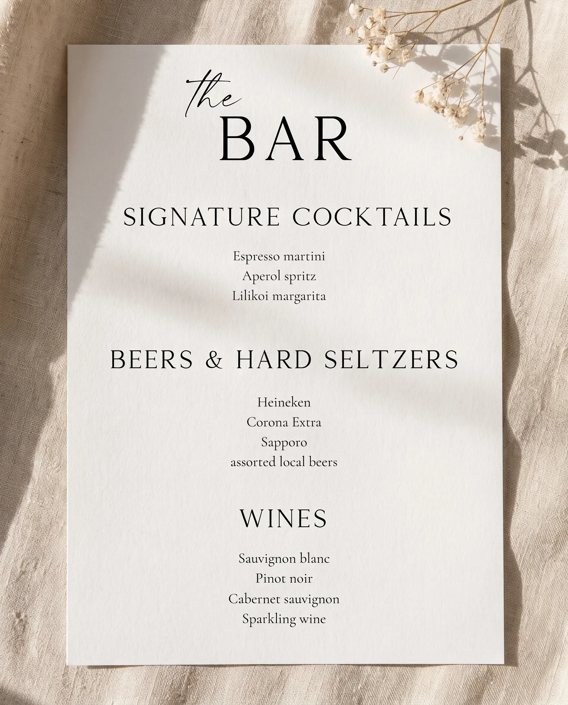Sunlit — bar menu page shown flat on premium editorial paper under soft natural light at a slight overhead angle, wedding bar menu.